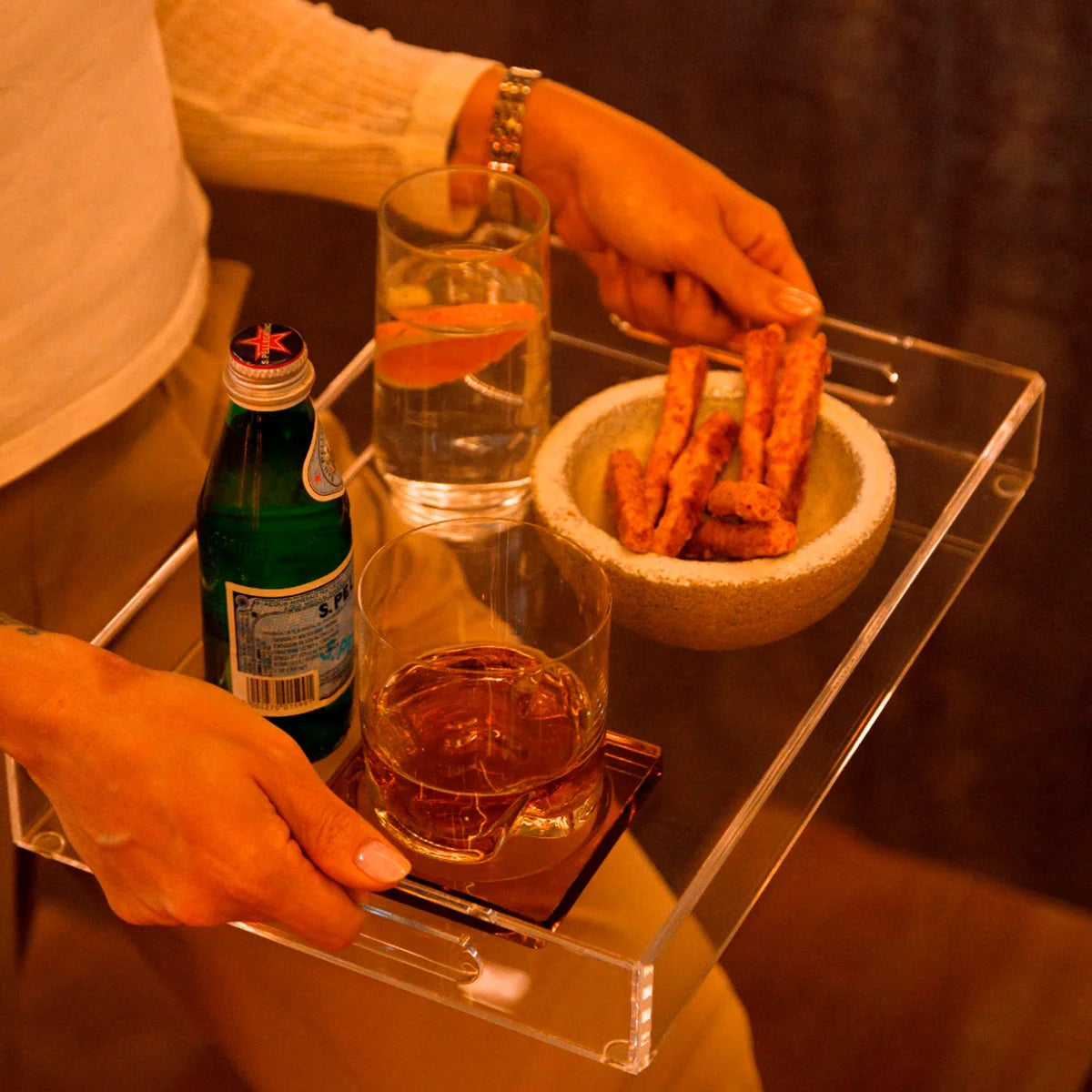 Bandeja Nítida em acrílico cristal, com bebidas e petiscos sendo transportados.