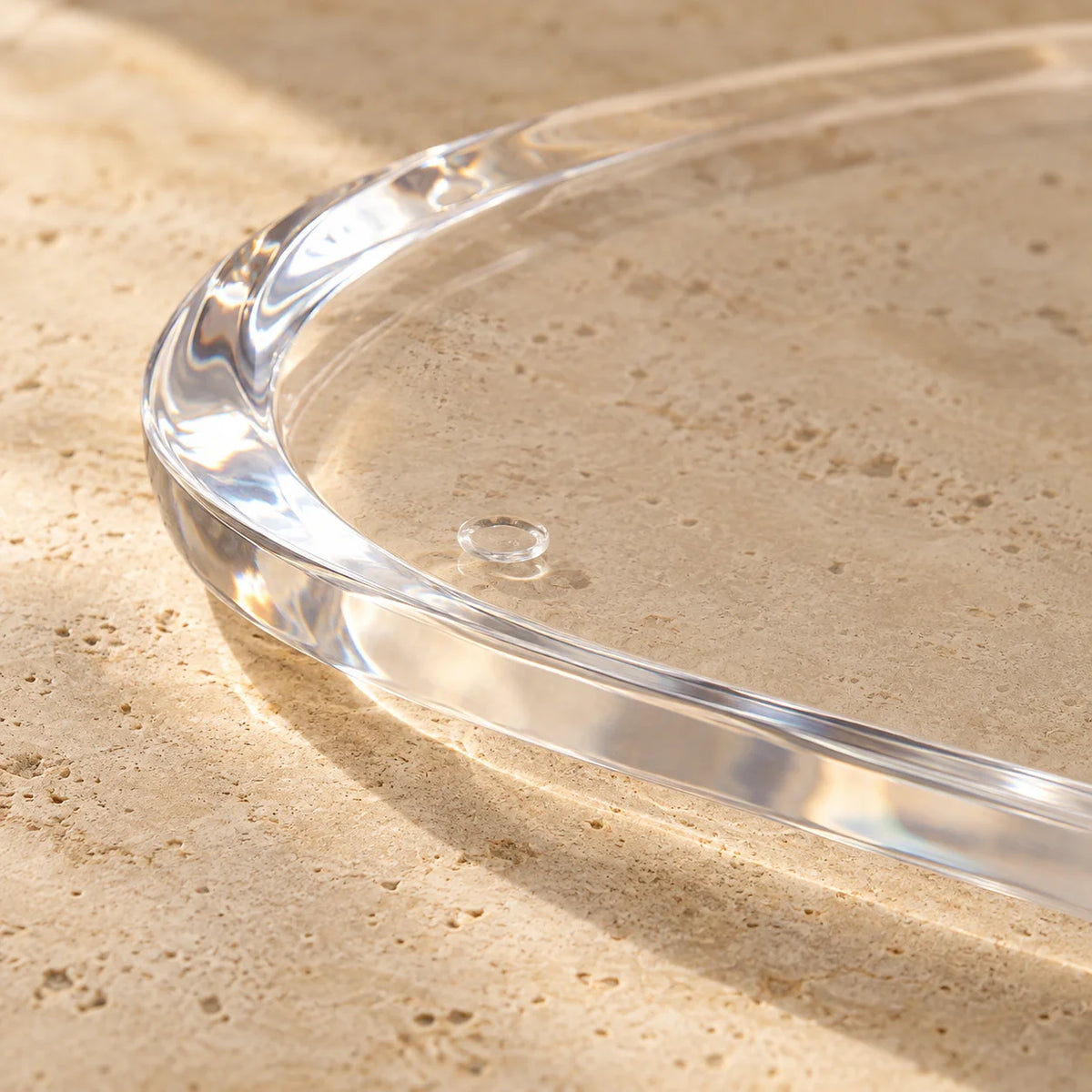 Base oval Elísea em acrílico cristal, em detalhe da borda transparente.