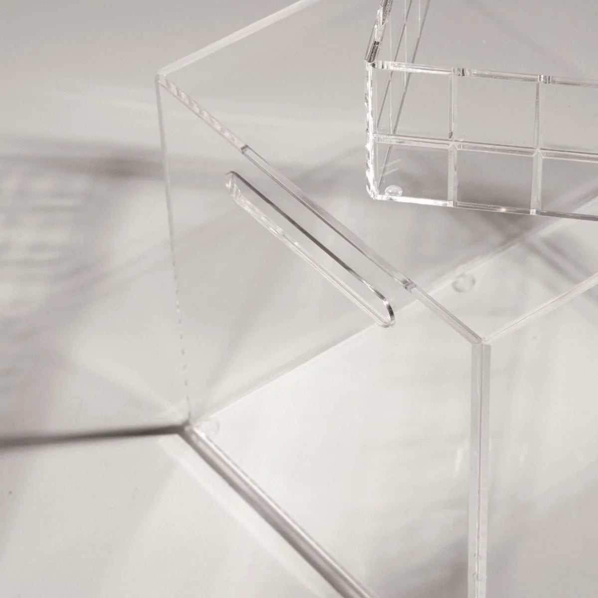 Caixa alta Velune em acrílico cristal, em detalhe da alça e da borda transparente.