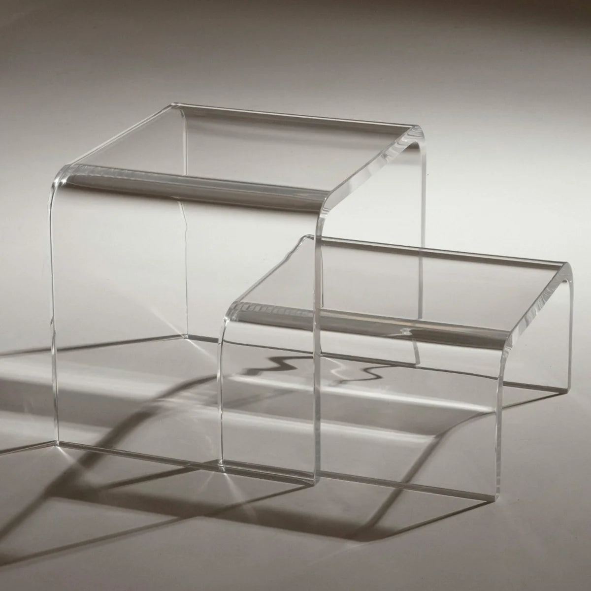 Escada modular Altea em acrílico cristal, com dois módulos sobre fundo cinza.