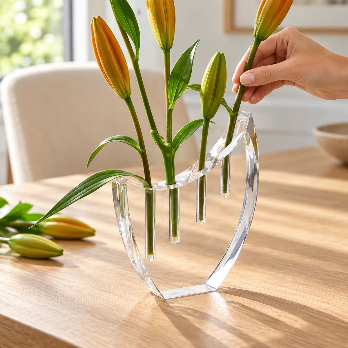 Vaso Selene em acrílico cristal, com mão posicionando uma haste floral.