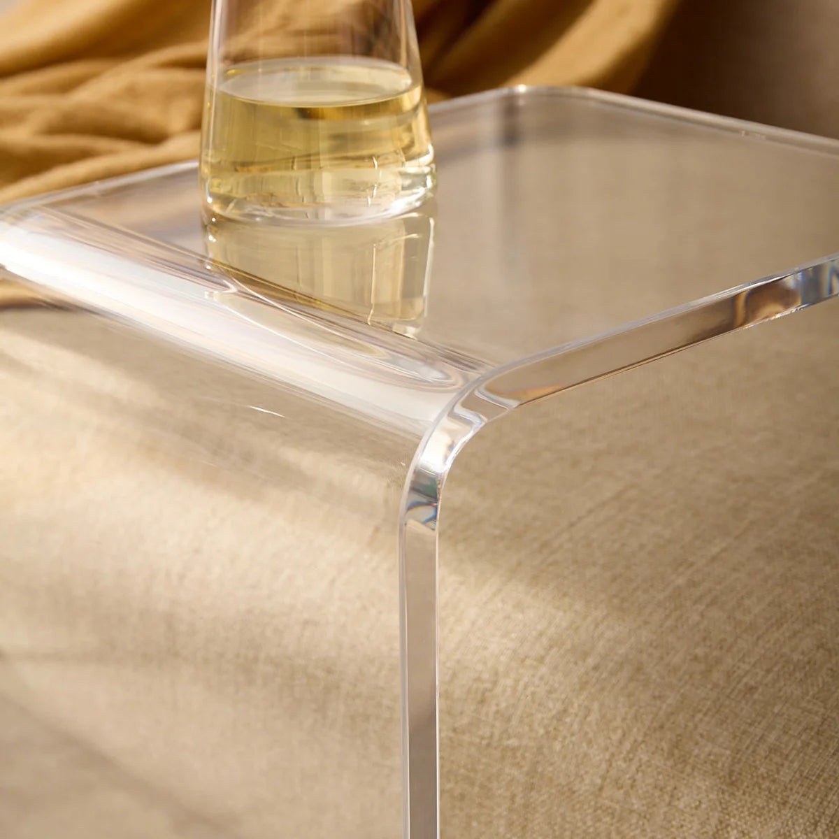 Aparador Claria em acrílico cristal, em aproximação da borda transparente e do copo.