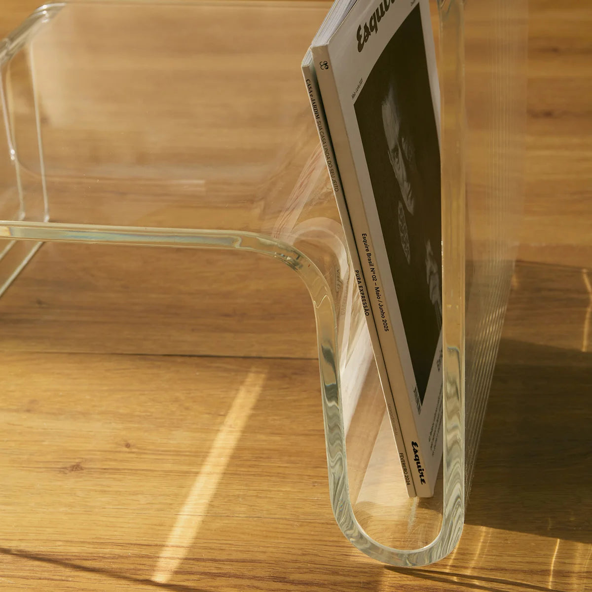 Mesa lateral Vértis em acrílico cristal, em detalhe da lateral com revista.