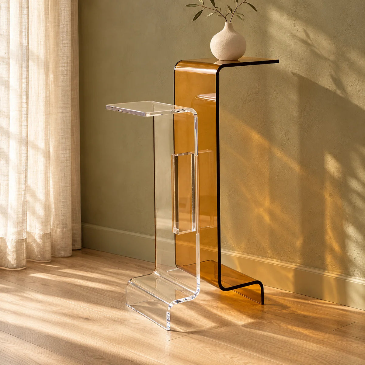 Aparador Bicroma em acrílico cristal e âmbar, com dois níveis e vaso em ambiente iluminado.