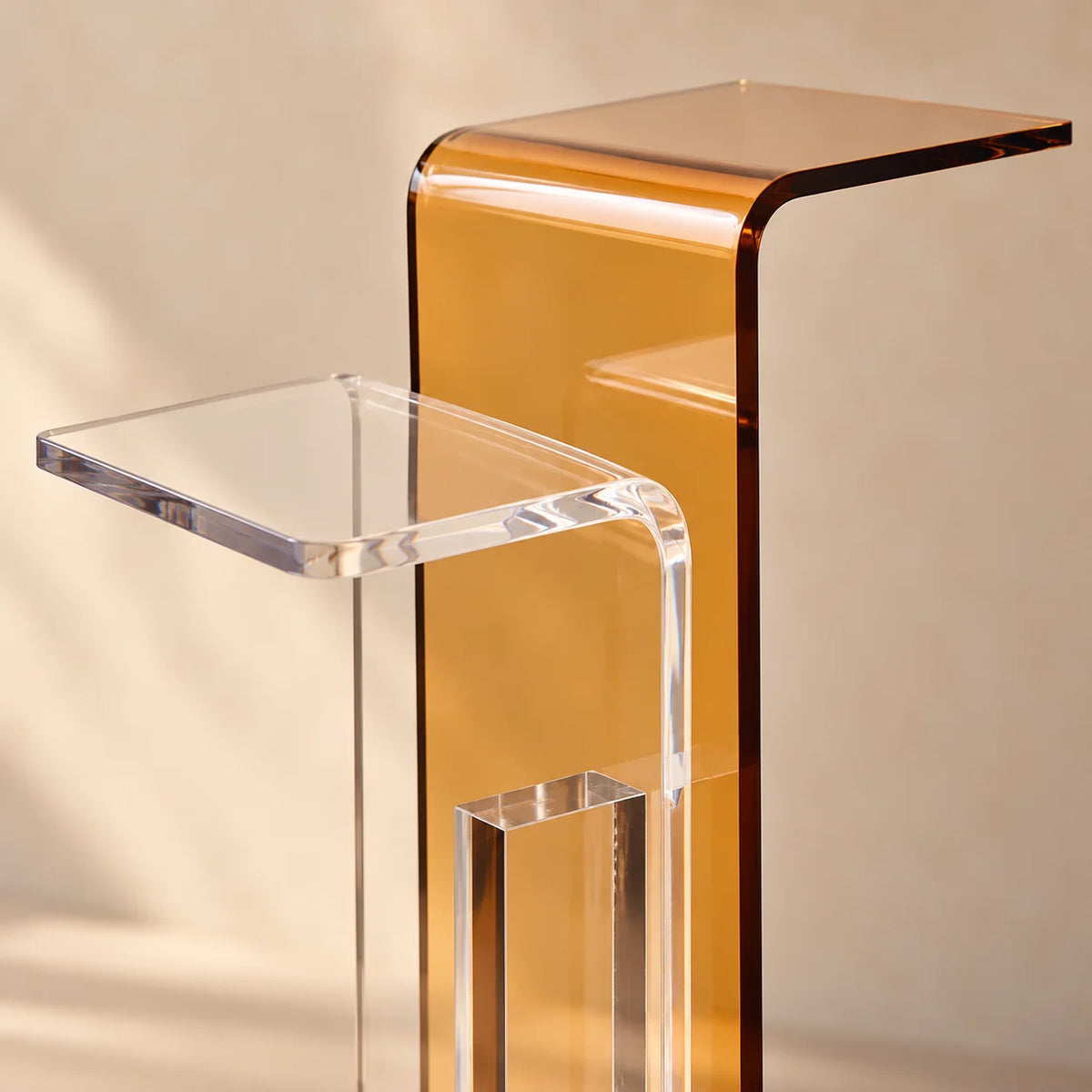 Aparador Bicroma em acrílico cristal e âmbar, em detalhe dos tampos transparente e âmbar.