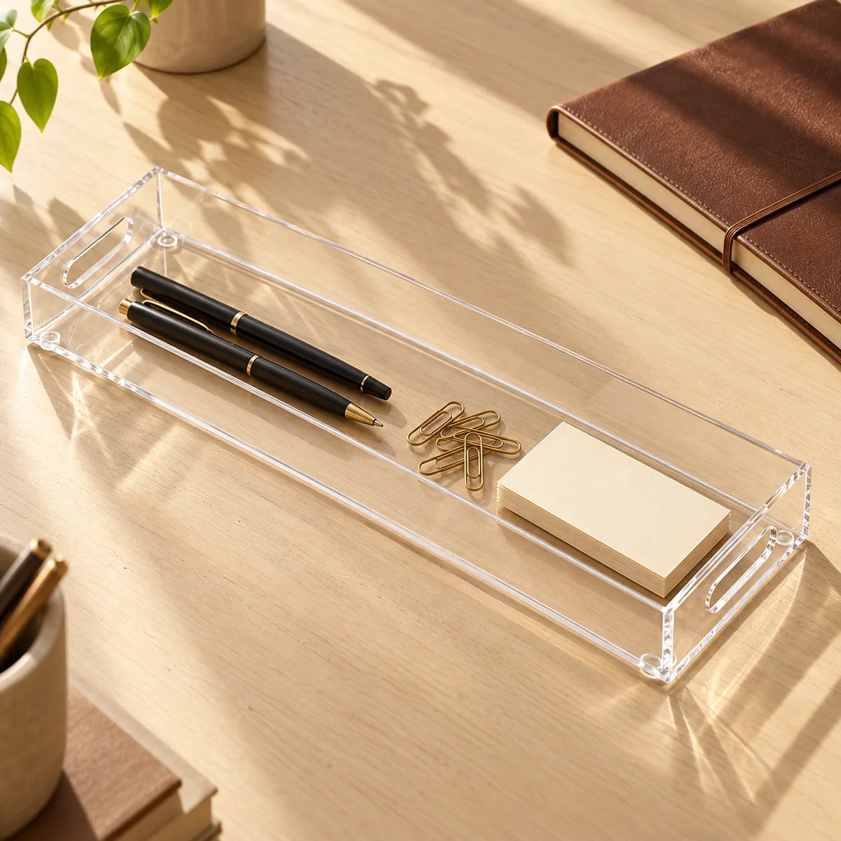 Bandeja Nítida em acrílico cristal, com canetas e pequenos itens de escritório.
