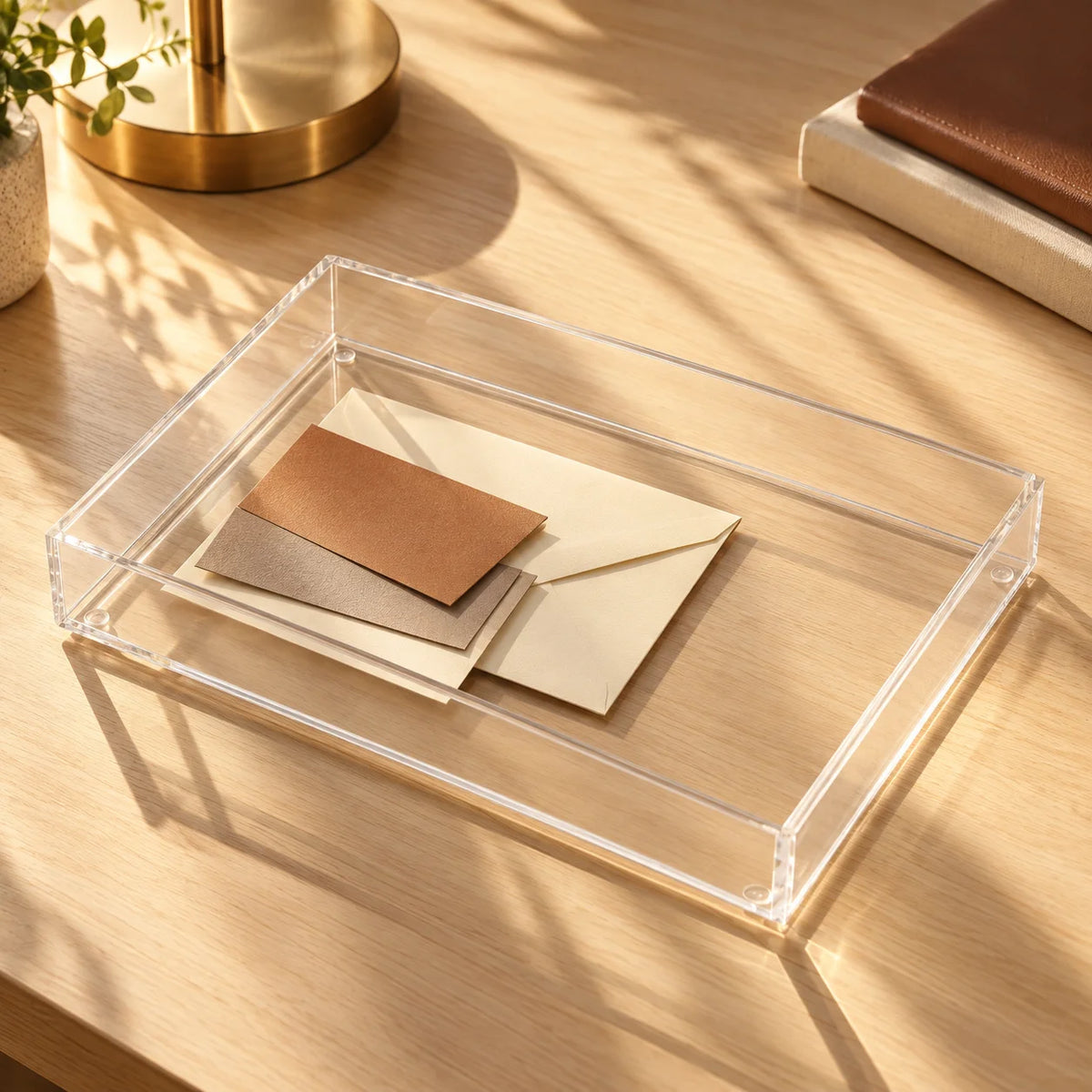 Caixa organizadora Velune em acrílico cristal, com caderno e envelopes sobre mesa.