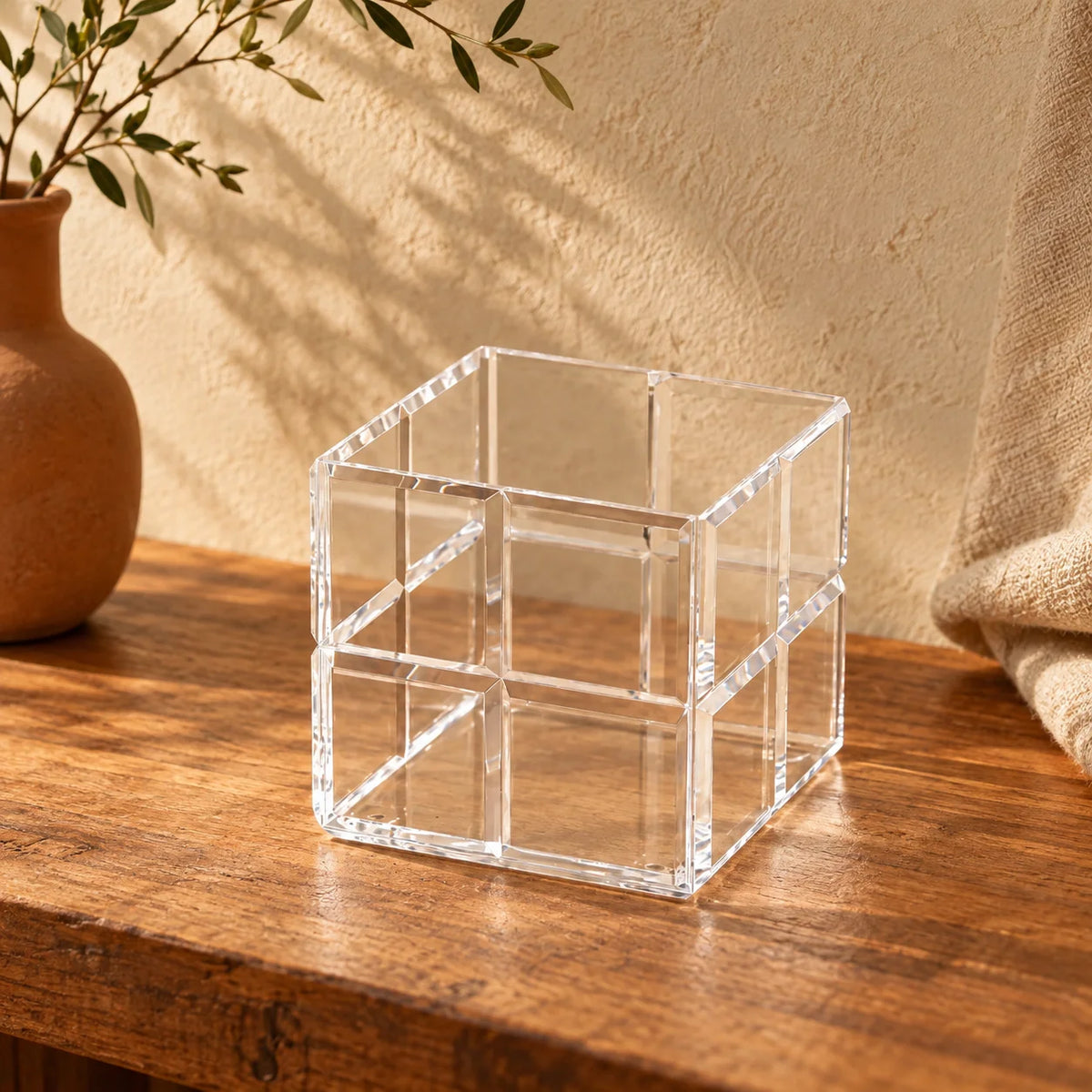 Cubo organizador Faceta em acrílico cristal, vazio sobre móvel de madeira.