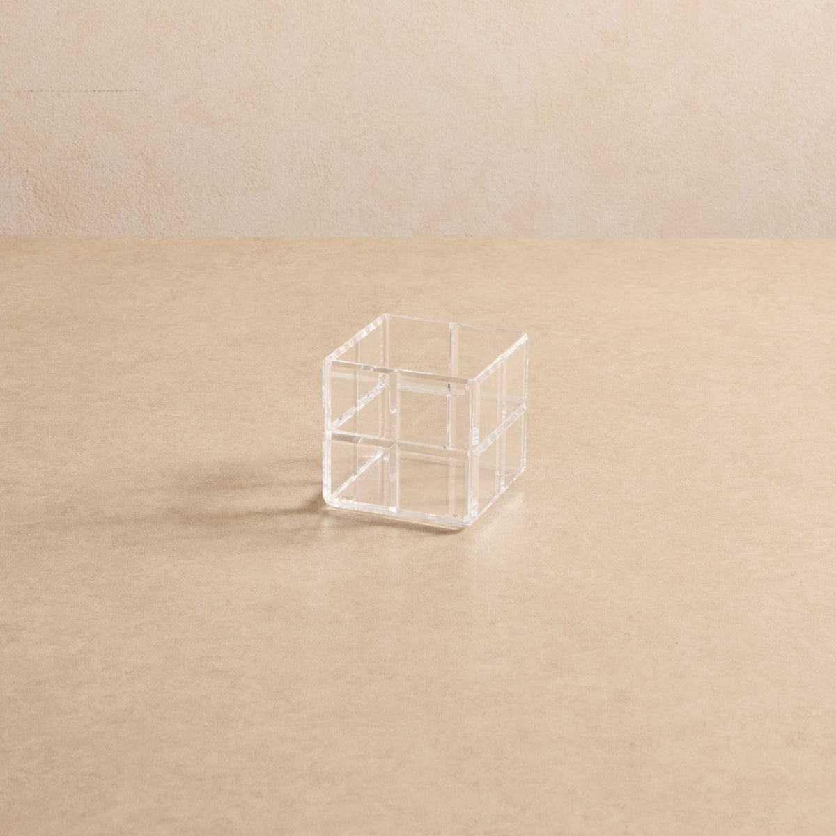 Cubo organizador Faceta em acrílico cristal, em vista ampla sobre fundo bege.