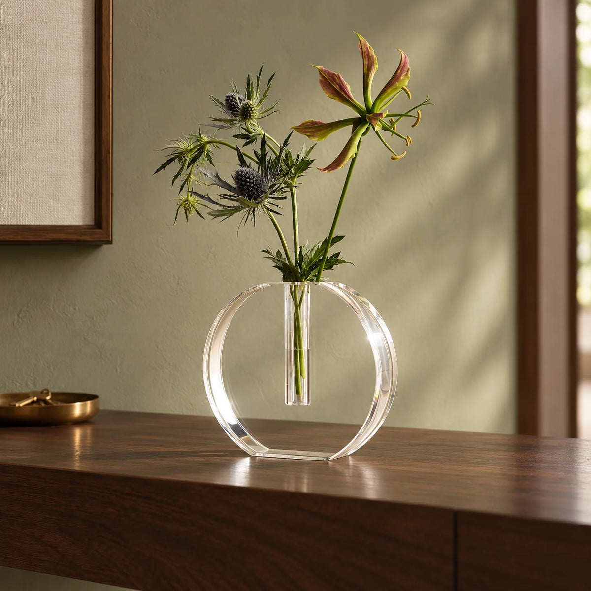 Vaso Sinué em acrílico cristal, com arranjo floral sobre aparador.