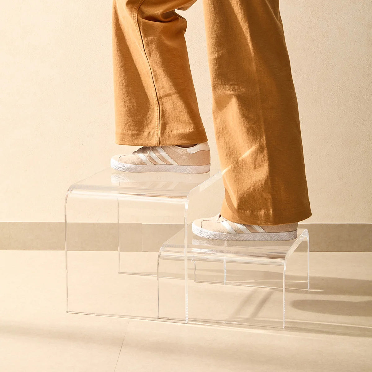 Escada modular Altea em acrílico cristal, em detalhe com pessoa de calça ocre e sapatos.