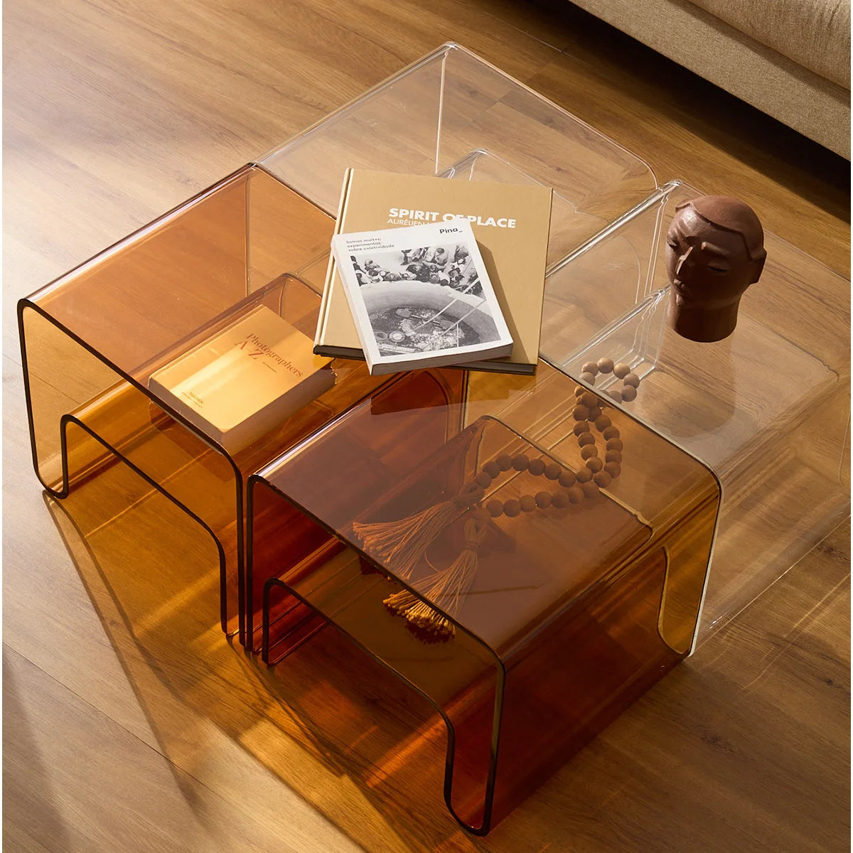 Mesa lateral Vértis em acrílico âmbar, em composição com versão transparente e livros.